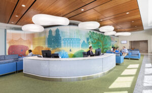 Photograph of the interior of NYU Hassenfeld Children's Hospital showing a Reception Desk with a large illustrated mural of Central Park on the wall behind